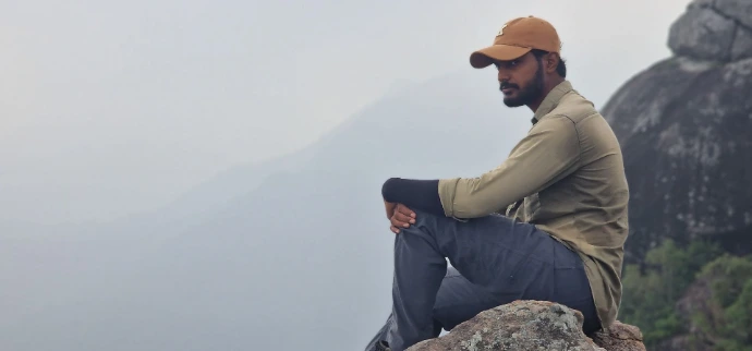 Man sitting on rock overlooking misty mountains during hike