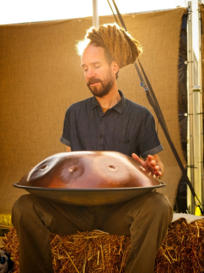 Musician playing handpan drum outdoors in natural light