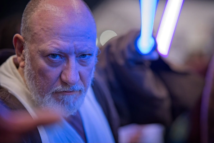 Portrait of cosplayer dressed as Jedi with blue lightsaber