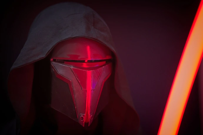 Cosplayer wearing red and black Sith mask with lightsaber