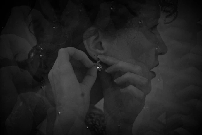 Abstract black and white double exposure of woman putting on an earring