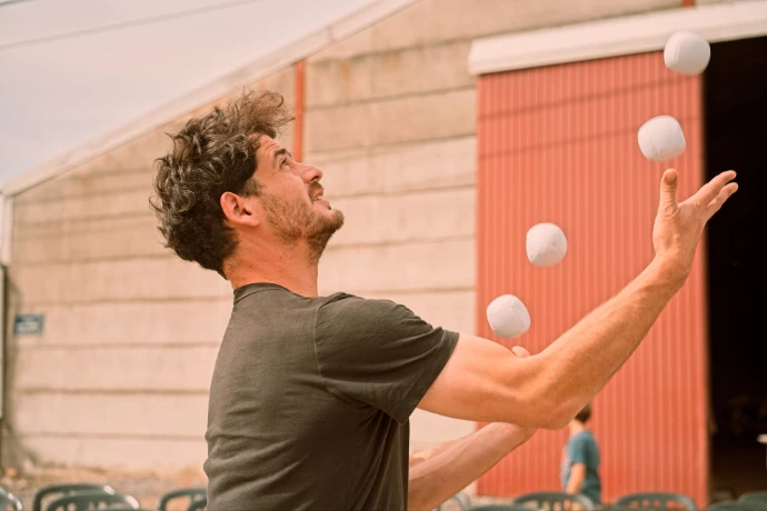 Performer juggling white balls at outdoor event