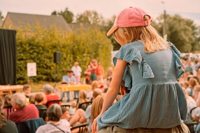 Mother and daughter watching performance at outdoor market festival