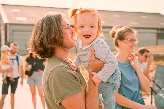 Father holding laughing toddler son outdoors in natural light