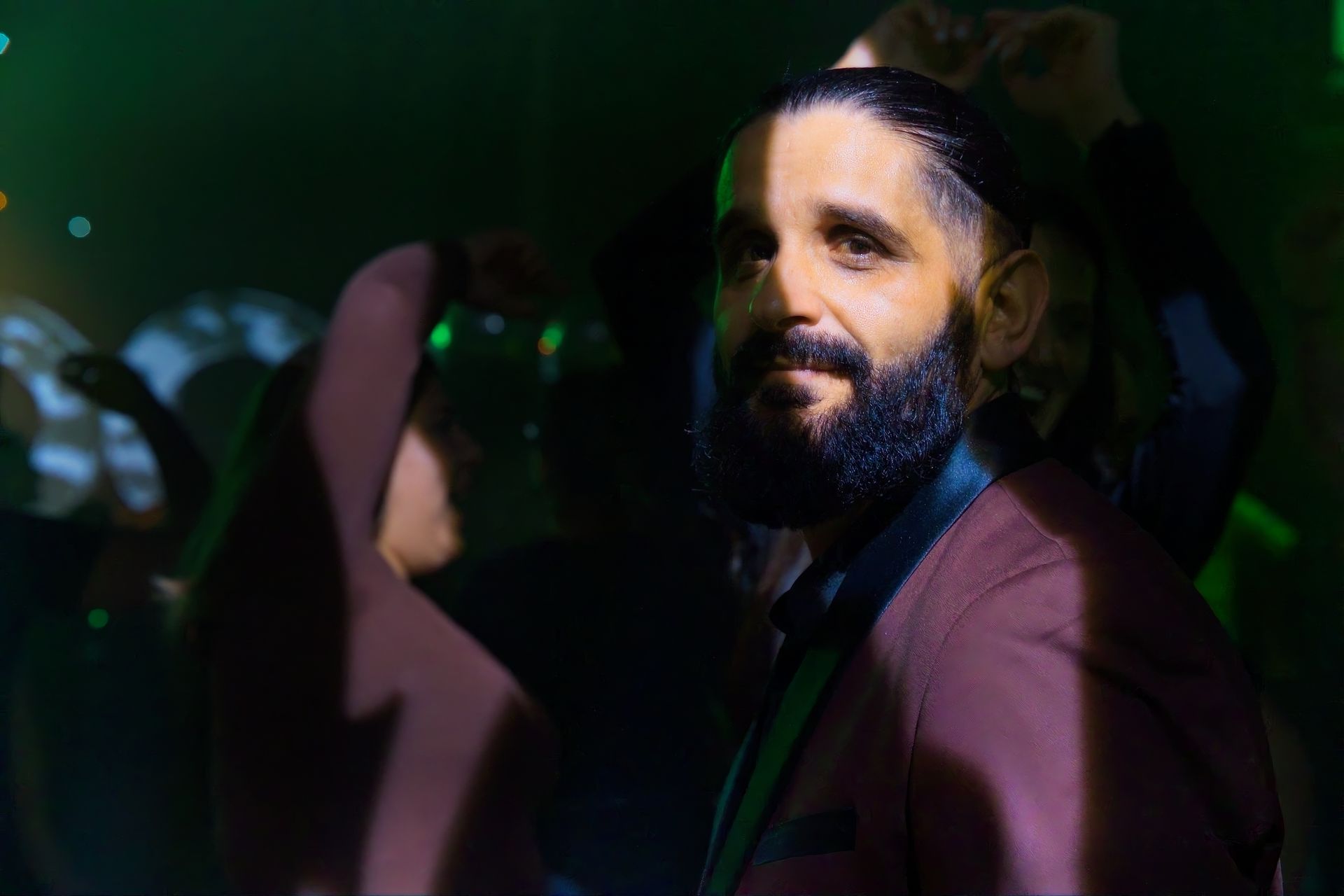 Portrait of bearded man in burgundy suit at corporate event with green lighting
