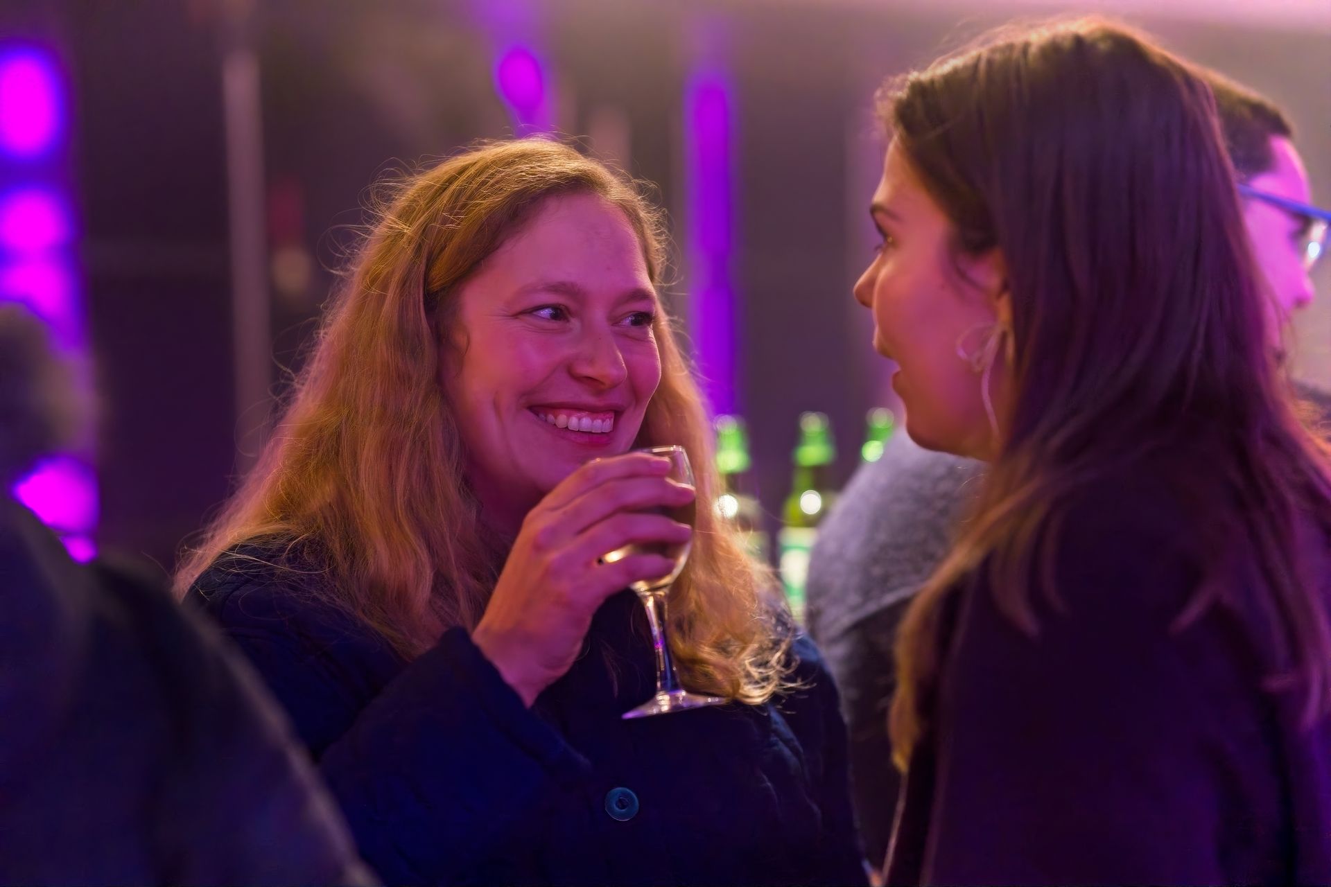 Two women talking and holding wine glasses at corporate networking event